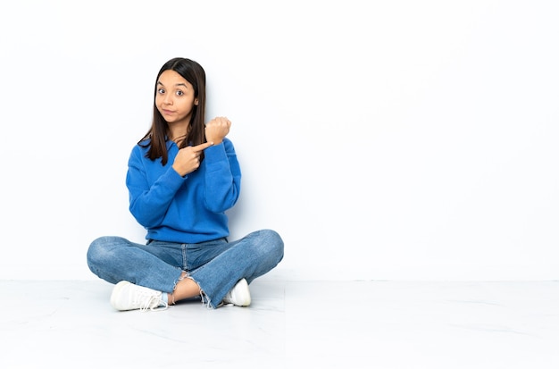 Young mixed race woman sitting on the floor isolated