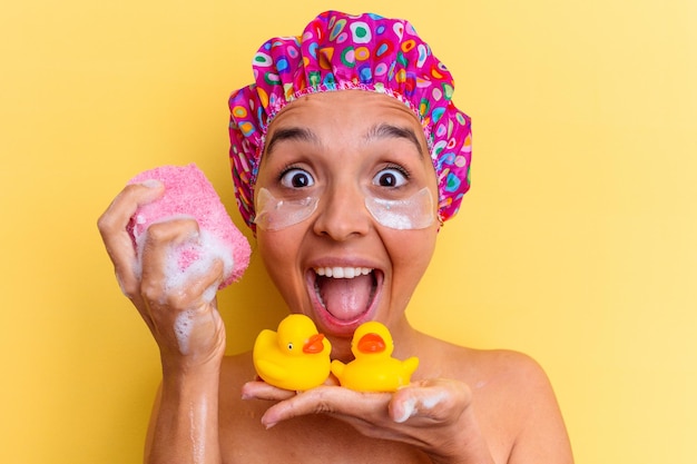 Young mixed race woman taking a bath holding a sponge and rubber ducks