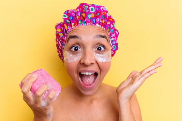 Young mixed race woman taking a bath holding a sponge with an under eye patches