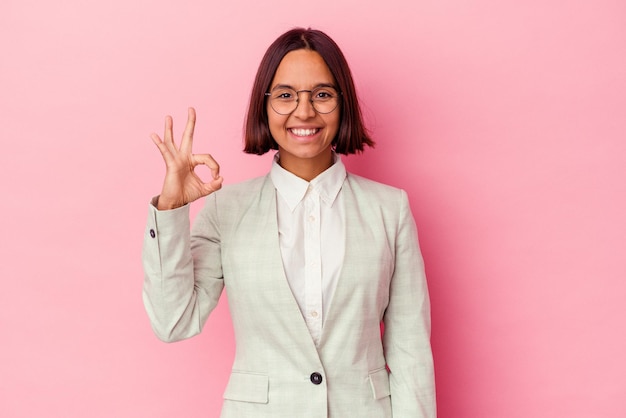 Young mixed race woman wearing a green suit isolated on pink background cheerful and confident showing ok gesture.