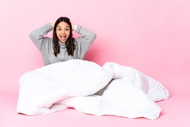 Young mixed race woman wearing pijama sitting on the floor laughing