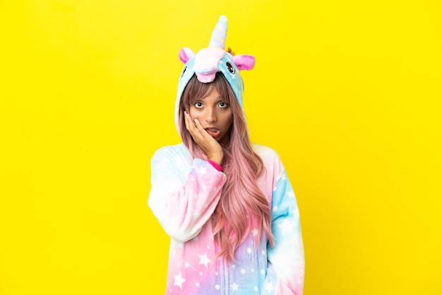 Young mixed race woman wearing a unicorn pajama isolated on white background surprised and shocked while looking right