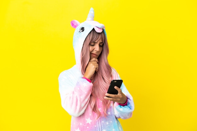 Young mixed race woman wearing a unicorn pajama isolated on white background thinking and sending a message