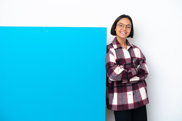 Young mixed race woman with a big blue placard isolated on white background keeping the arms crossed in frontal position