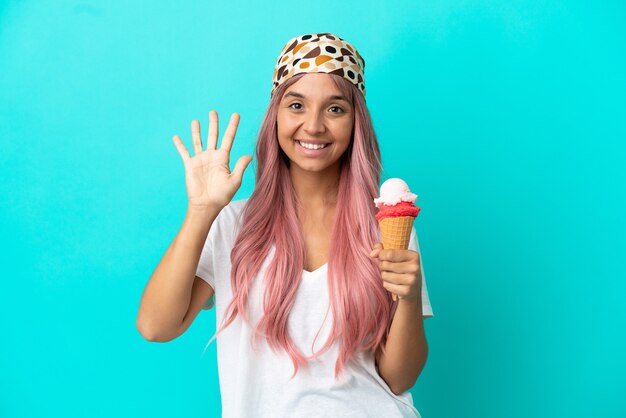 young mixed race woman with a cornet ice cream isolated on blue background counting five with fingers