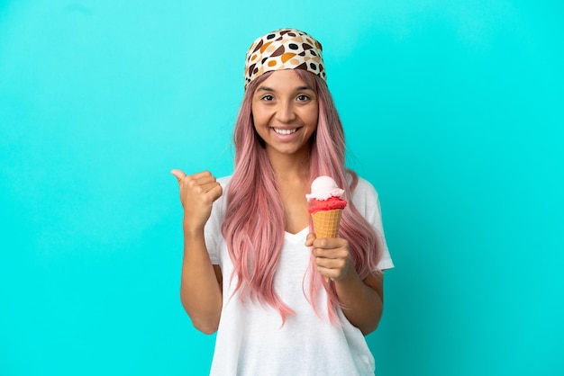 Young mixed race woman with a cornet ice cream isolated on blue background pointing to the side to present a product