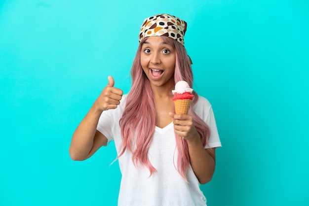 young mixed race woman with a cornet ice cream isolated on blue background with thumbs up because something good has happened