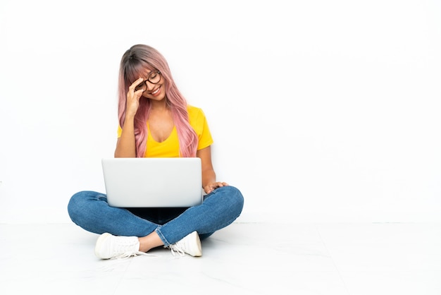 Photo young mixed race woman with a laptop with pink hair sitting on the floor isolated on white background laughing