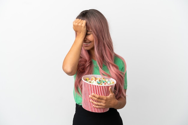 Young mixed race woman with pink hair eating popcorn isolated on white background has realized something and intending the solution