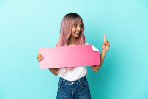 Young mixed race woman with pink hair isolated on blue background holding an empty placard and thinking