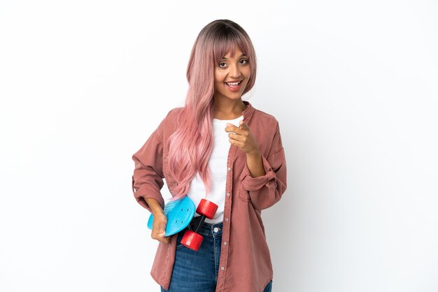 Young mixed race woman with pink hair isolated on white background with a skate and pointing to the front