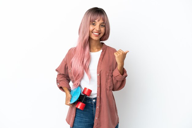 Young mixed race woman with pink hair isolated on white background with a skate and pointing to the side