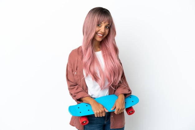 Young mixed race woman with pink hair isolated on white background with a skate with happy expression