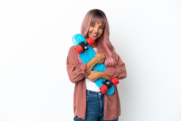 Young mixed race woman with pink hair isolated on white background with a skate with happy expression