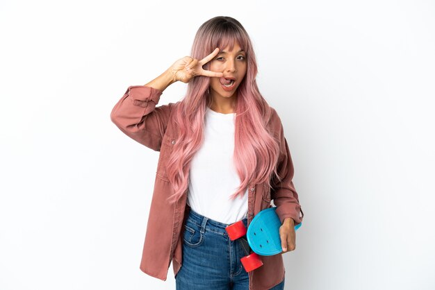 Young mixed race woman with pink hair isolated on white background with a skate with happy expression