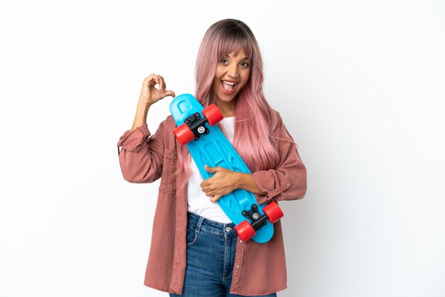 Young mixed race woman with pink hair isolated on white background with a skate with happy expression