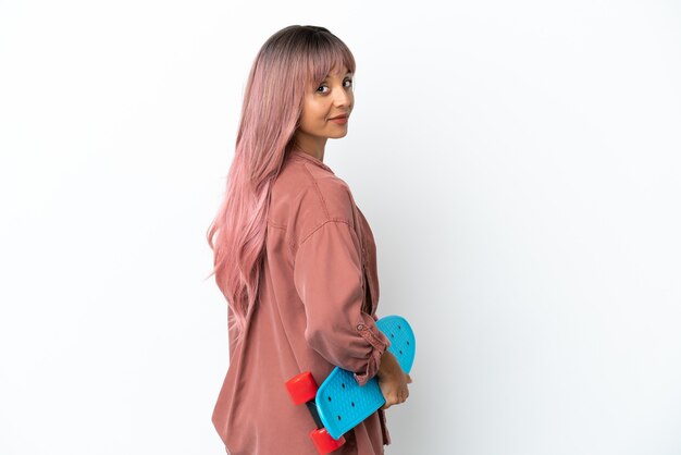 Young mixed race woman with pink hair isolated on white background with a skate