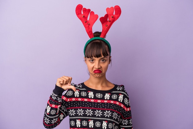 Young mixed race woman with reindeer hat celebrating Christmas isolated on purple background  showing a dislike gesture, thumbs down. Disagreement concept.