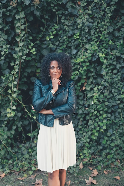 Young mixed woman with afro hairstyle smiling in urban background. Black girl wearing casual clothes. 