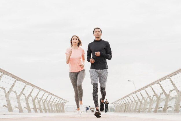 Young mixedrace fit friends couple boyfriend and girlfriend\
athletes jogging running