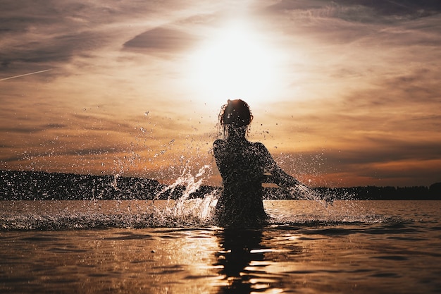 Foto giovane modello che nuota nell'ora del tramonto del mare