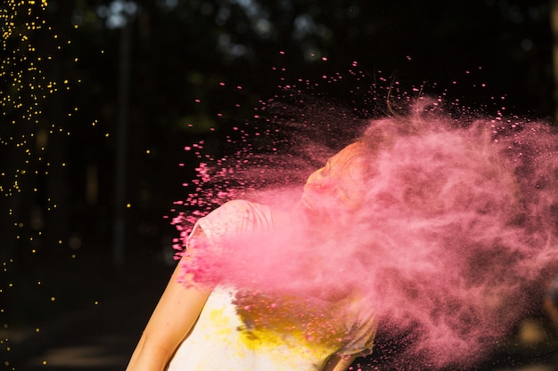 Young model with hair in wind posing covered with pink powder Holi