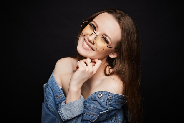 Young model woman in trendy glasses and denim jacket posing