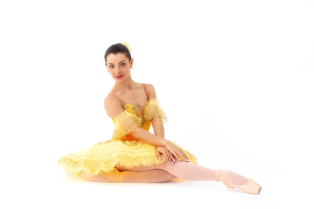 Young modern ballerina with yellow tutu doing the pose.