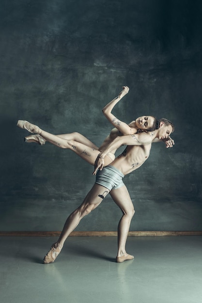 The young modern ballet dancers posing on gray studio background