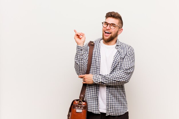 Young modern business man smiling cheerfully pointing with forefinger away.