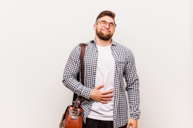 Young modern business man touches tummy, smiles gently, eating and satisfaction concept.