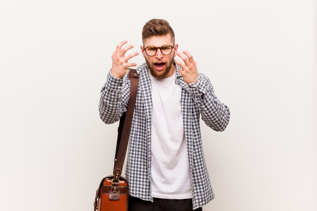 Young modern business man upset screaming with tense hands.