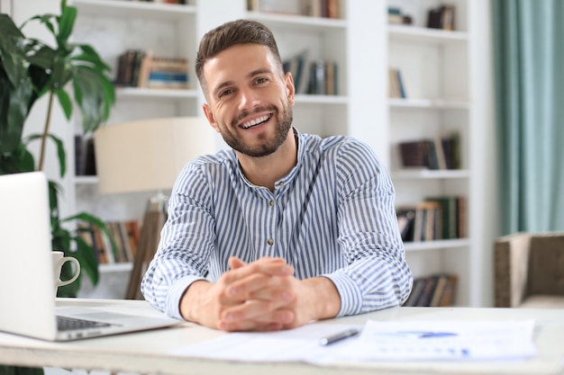 Young modern business man working using laptop while sitting in the office.