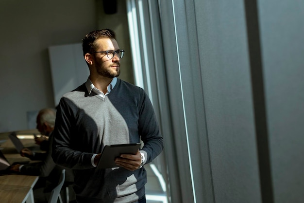 Young modern businessman using digital tablet in the office