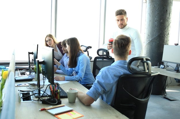 Young modern colleagues in smart casual wear working together while spending time in the creative office.