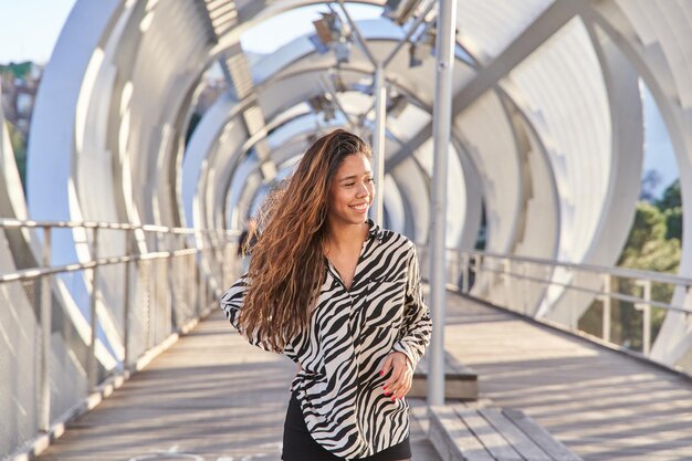 young modern latina posing looking at the camera walking around the city smiling