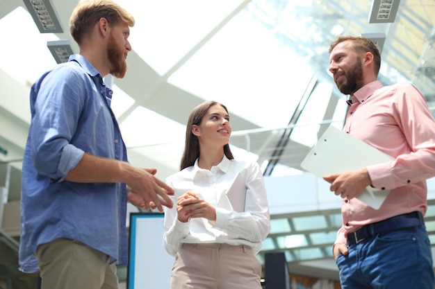 Young modern people in smart casual wear discussing business while standing in creative office