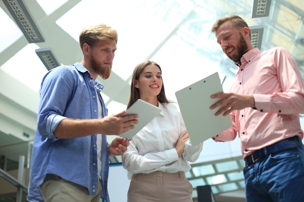 Young modern people in smart casual wear discussing business while standing in creative office