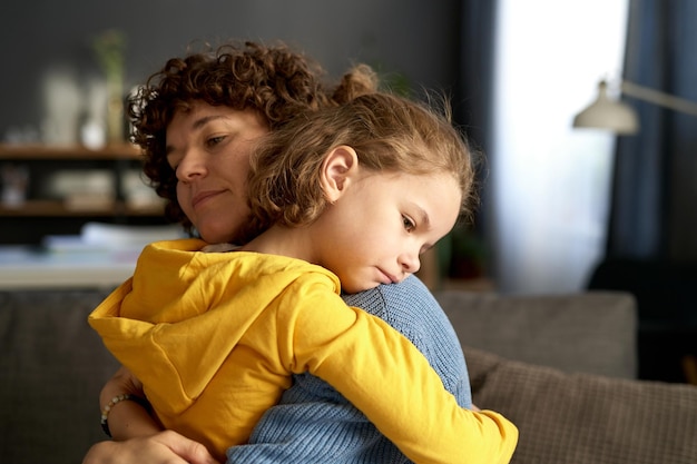 Young mom embracing and calming her child while he in bad mood or upset feelings