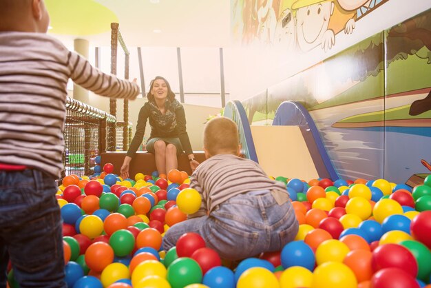 young mom playing with kids in pool with colorful balls