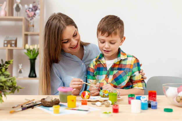 Photo young mom and son painting eggs for easter