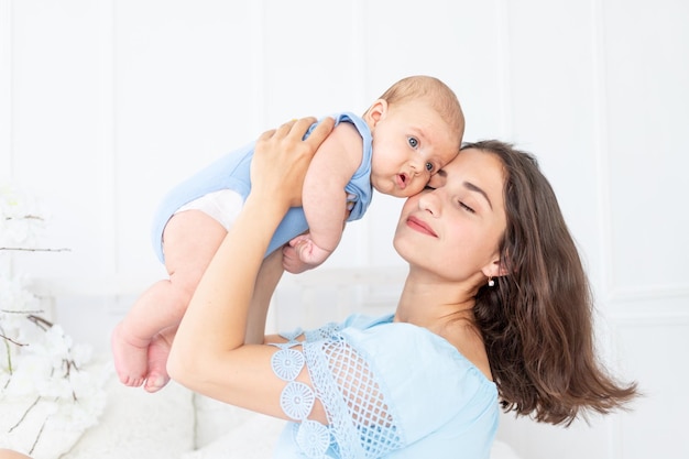 La giovane mamma con il neonato si coccola a casa sul letto, sulla famiglia felice e sul concetto di compleanno