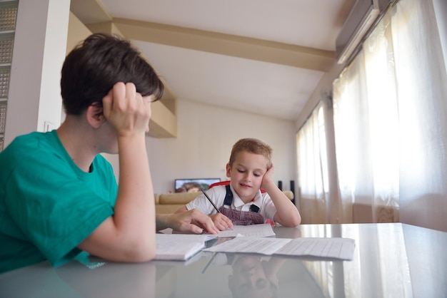 young mom woman doing home work with elementary school grade boy at home in kitchen