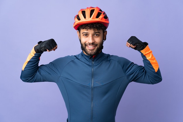 Young Moroccan cyclist man isolated on purple doing strong gesture