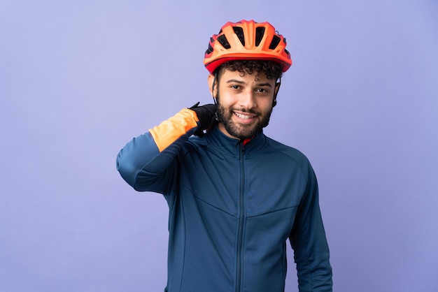 Young Moroccan cyclist man isolated on purple laughing