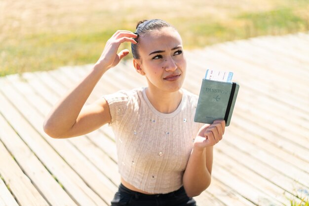 屋外でパスポートを保持している若いモロッコの女の子は、疑問を持ち、混乱した表情をしています