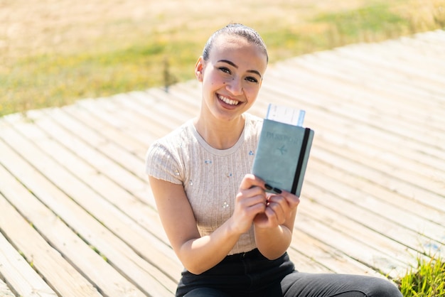 幸せな表情で屋外でパスポートを保持している若いモロッコの女の子