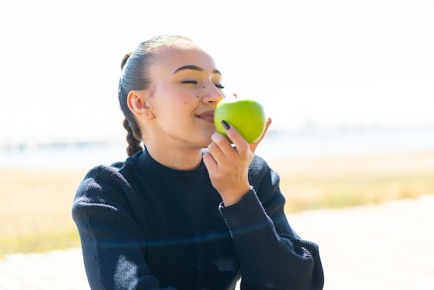 Молодая марокканская девушка на улице держит яблоко