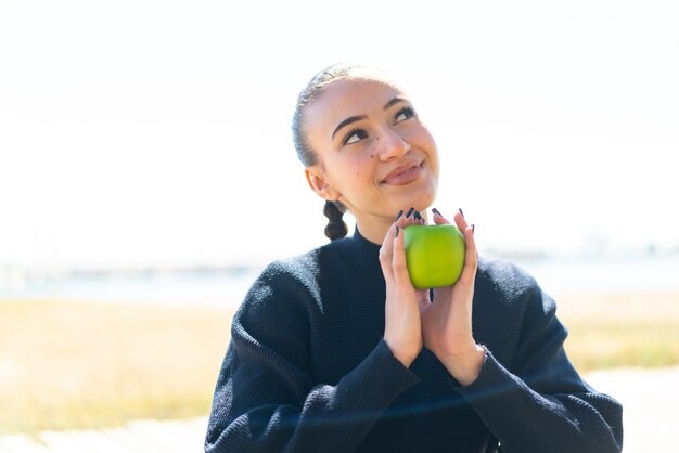 Young moroccan girl at outdoors holding an apple