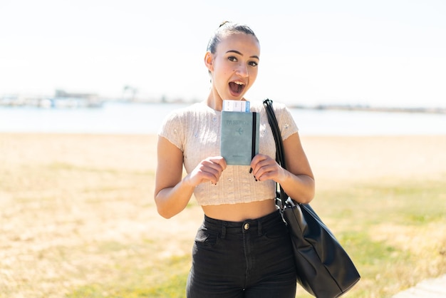 Young moroccan girl at outdoors holding a passport with surprised expression